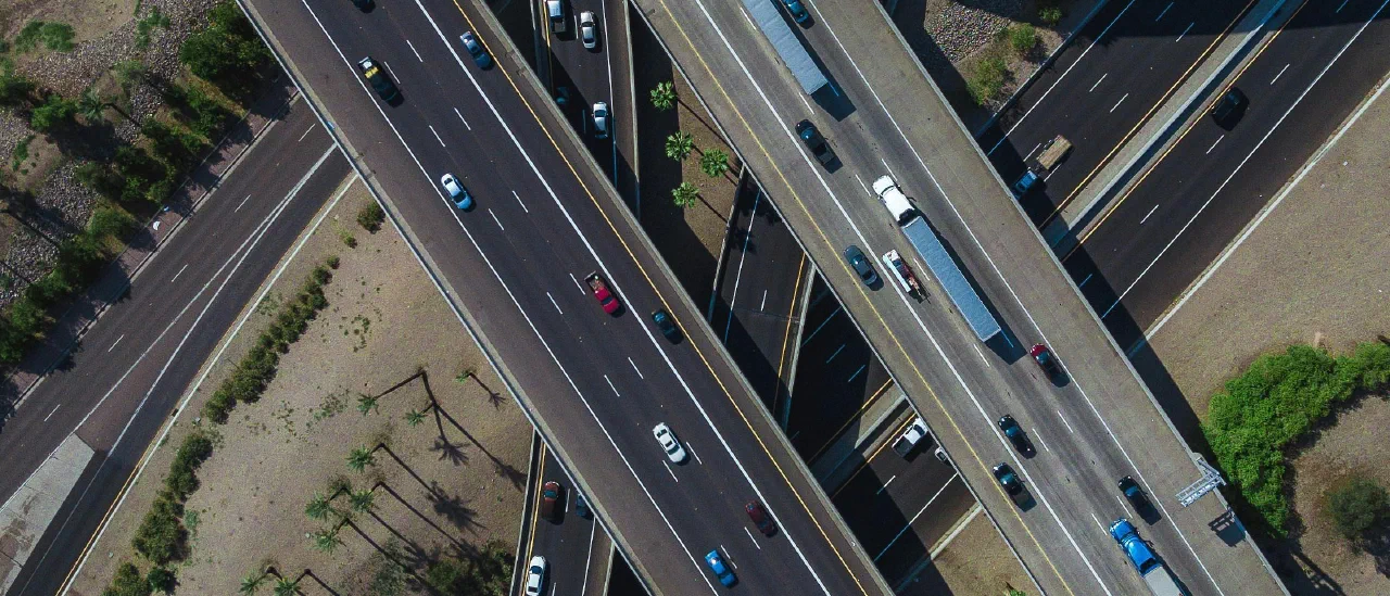 Luftaufnahme eines mehrstöckigen Autobahnkreuzes, auf dem sich Fahrspuren in mehreren Ebenen kreuzen und überlagern