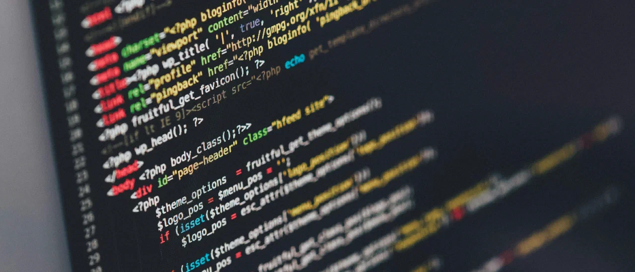 Angled close-up of a monitor showing syntax-highlighted HTML and PHP source code